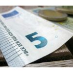 Primo piano di una banconota da 5 euro sbiadita, simbolo del suo declino economico.